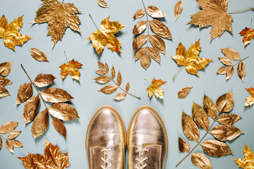 Autumn composition. Pattern made of autumn golden  leaves and stylish shoes on  blue background. Flat lay, top view