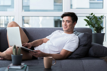 Cheerful young man is working at home