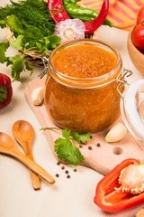 Tomato sauce (ketchup, adzhika) and vegetables on a beige table. Home preservation.