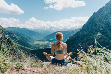 young girl meditates on a background of mountains