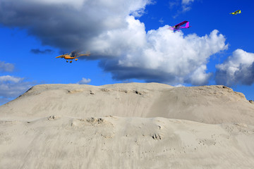 Trzy samolotu, awionetki w chmurach nad ogromną górą piachu. - obrazy, fototapety, plakaty