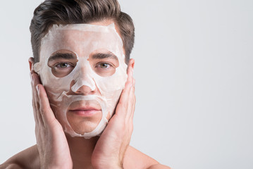 Serious guy is enjoying moisturizing procedure