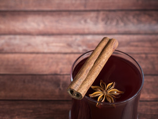 Glass Cup of red wine mulled wine on a wooden background with cinnamon background.