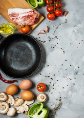 Products for breakfast, eggs, bacon, vegetables, herbs on stone background, top view with copy space.