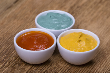 Red tomato sauce, turmeric sauce and spirulina sauce on the wooden background