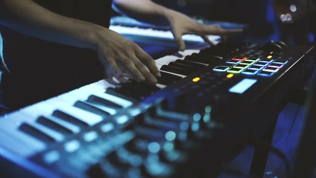 Musician playing on the keyboard synthesizer piano keys. Musician plays a musical instrument on the concert stage