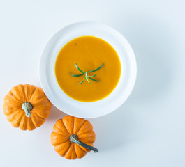 Pumpkin soup with rosemary in white plate