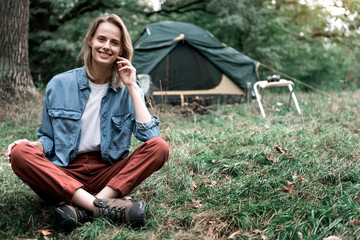 Joyful young woman sitting on grass in the nature