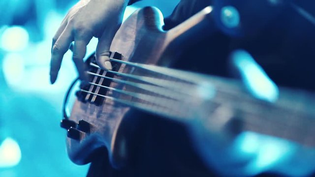 Man bass guitarist playing electrical guitar on concert stage 