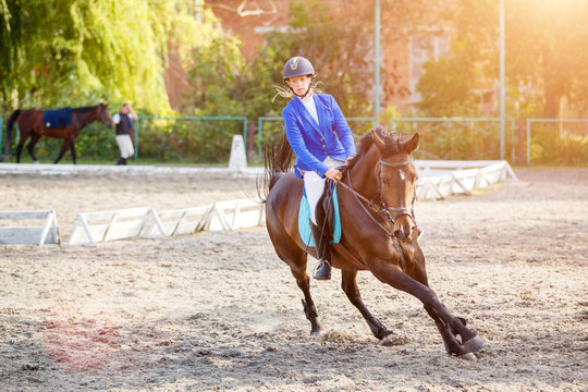 Young girl on bay horse galloping on her course on show jumping competition