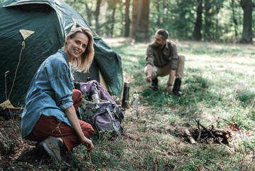 Joyful married couple pitching shelter in the nature