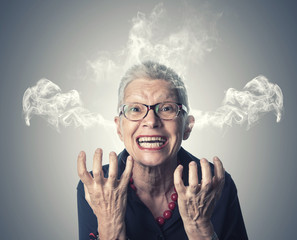 Furious and enraged senior elderly lady with smoke coming out of her ears