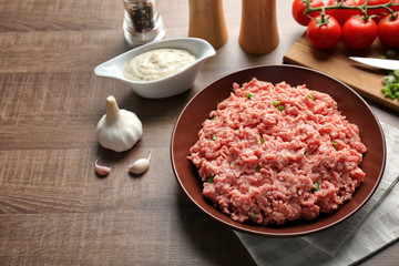 Plate with fresh raw minced meat on table