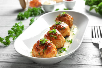 Plate with delicious meatballs on wooden table