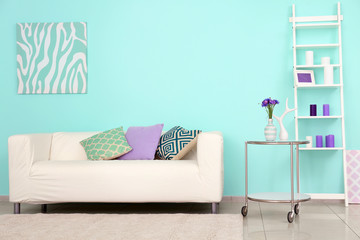 Lilac accent in modern interior. Comfortable couch and table with flowers in living room