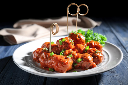 Plate with delicious meatballs on wooden table