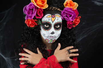 Sugar Skull little girl Halloween costume and makeup. Portrait of a little girl with Halloween costume and makeup of Sugar Skull with white painted face, roses
