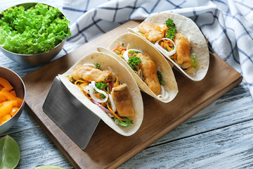 Stand with delicious fish tacos on wooden table