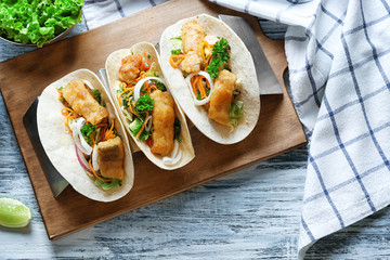 Stand with delicious fish tacos on wooden table