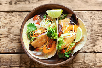 Plate with delicious fish tacos on wooden table