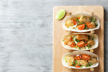 Stand with delicious fish tacos on wooden background