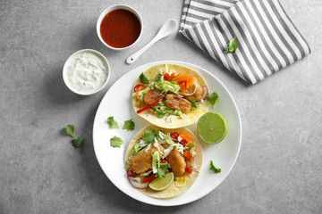 Plate with delicious fish tacos on table