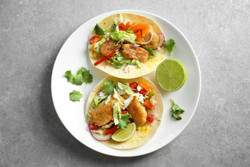 Plate with delicious fish tacos on table