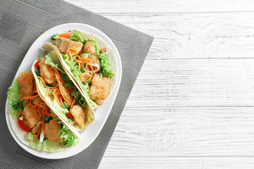 Plate with delicious fish tacos on wooden table