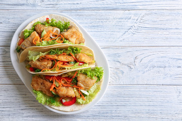 Plate with delicious fish tacos on wooden table