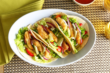 Bowl with delicious fish tacos on table, closeup