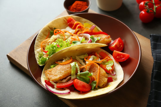 Plate with delicious fish tacos on table