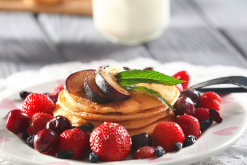 Plate with tasty pancakes and berries on table, closeup