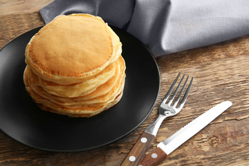 Plate with tasty pancakes on wooden table