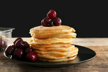 Plate with tasty pancakes and berries on wooden table