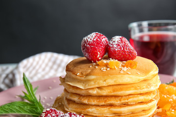 Tasty pancakes with dried apricots and strawberry on plate