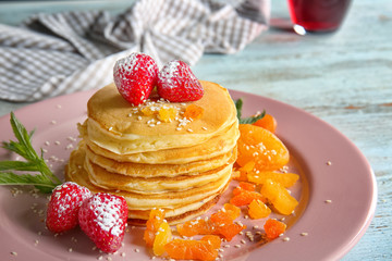 Plate with tasty pancakes, dried apricots and strawberry on wooden table