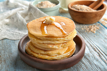 Plate with tasty pancakes on wooden table