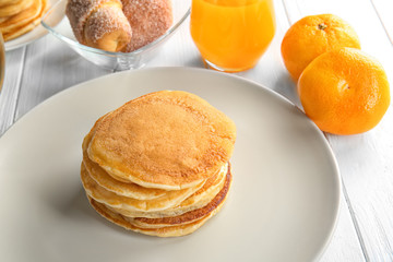 Plate with tasty pancakes on wooden table