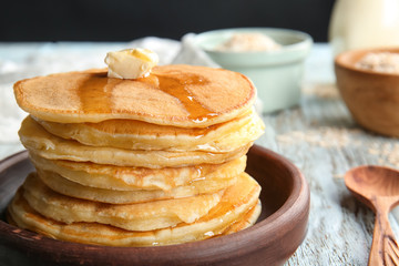 Plate with tasty pancakes on wooden table