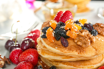 Plate with tasty pancakes, walnuts, dried fruits and berries, closeup