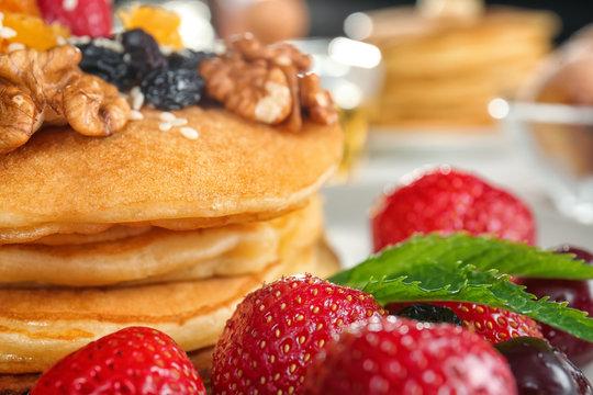 Tasty pancakes with walnuts, dried fruits and berries, closeup