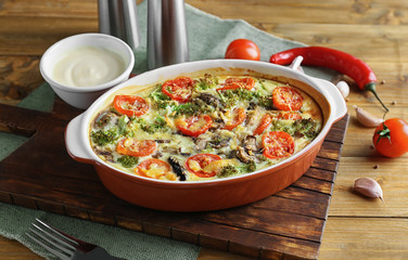 Baking dish with tasty broccoli casserole on wooden table