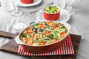 Baking dish with tasty broccoli casserole on table