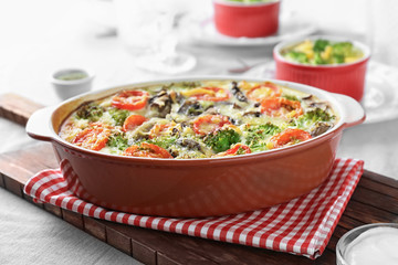 Baking dish with tasty broccoli casserole on table