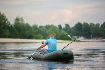 Man fishing from inflatable boat on river