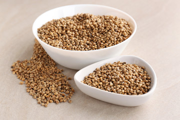 Bowls with hemp seeds on light background