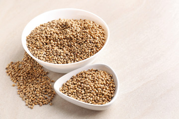 Bowls with hemp seeds on light background