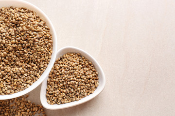 Bowls with hemp seeds on light background