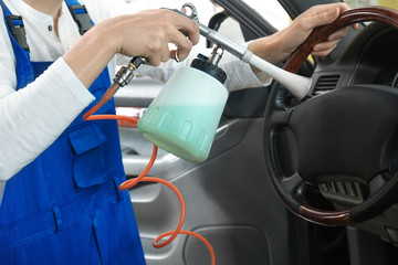 Young man cleaning car salon in body shop