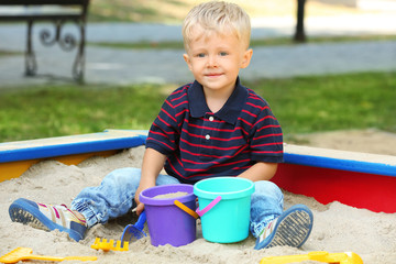 Cute little boy playing in sandbox, outdoors